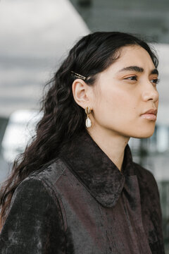 portrait of a young woman with shell earrings and a collared shirt