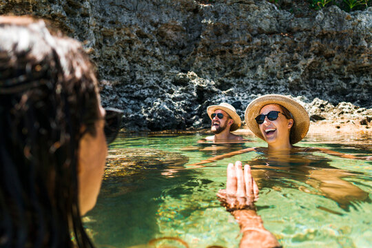 Group of friends joyning sun bath in natural pool in reef