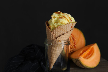 Delicious melon ice cream in wafer cone and glass jar on table, closeup