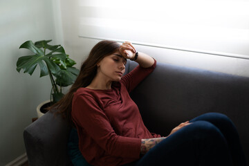 Fototapeta premium Young woman sick with depression sitting on the couch