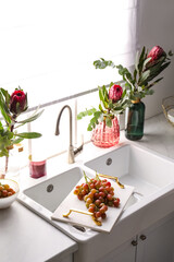 Vases with beautiful protea flowers near sink in kitchen. Interior design