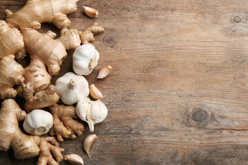 Fototapeta na wymiar Ginger and fresh garlic on wooden table, flat lay with space for text. Natural cold remedies