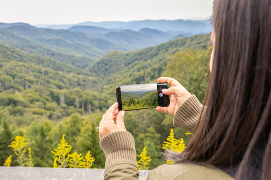 Young female taking a picture of the mountain view with her mobile phone.