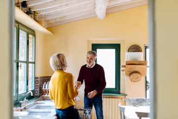 Mature couple talking while washing dishes