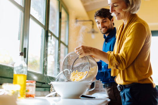 Mother and son cooking pasta together