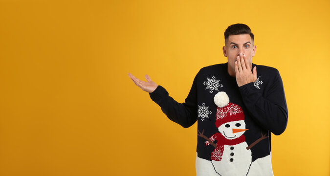 Shocked man in Christmas sweater on yellow background
