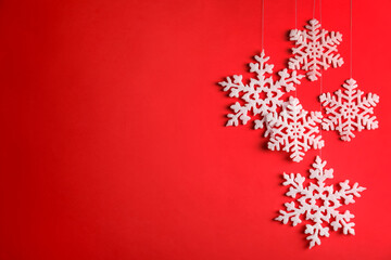 Beautiful decorative snowflakes hanging on red background, space for text