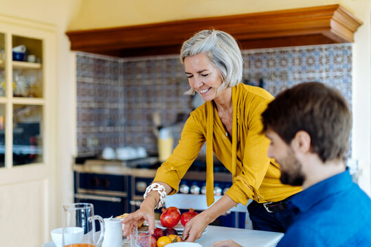 Cheerful woman preparing table for family breakfast