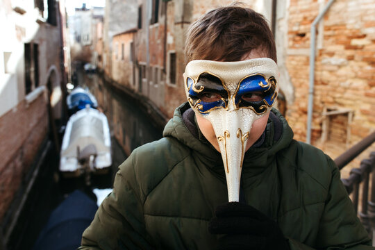 A young boy in a paper carnival mask.
