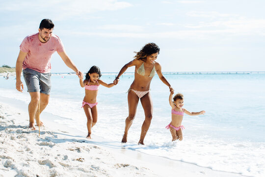 Happy multiracial family running on beach