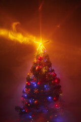 Christmas tree with festive lights, orange background with smoke