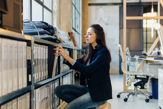 Female employee taking folder from shelf