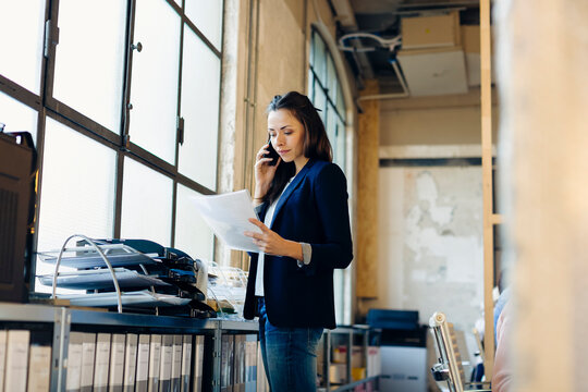Smart woman with document speaking on smartphone