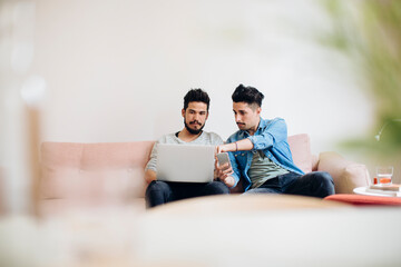 Trendy ethnic boyfriends using gadgets together