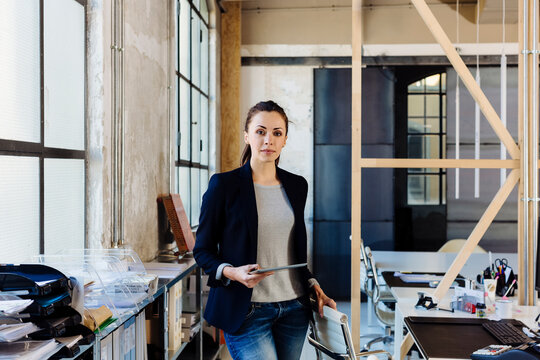 Female employee with tablet standing in creative workplace