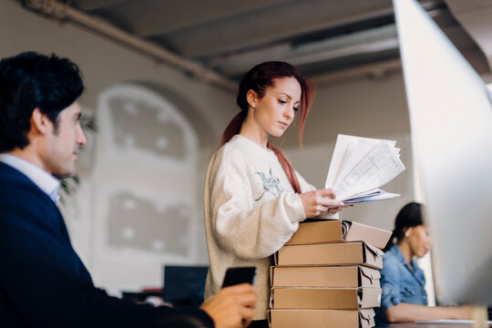 Young woman reading papers near colleagues