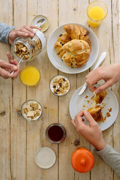 Crop couple having breakfast on wooden table