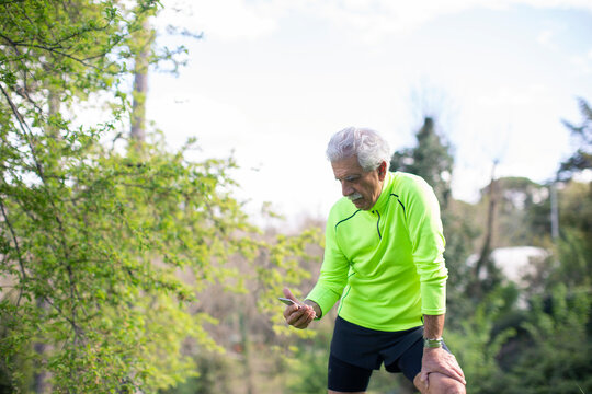 Senior athlete using smartphone during training in park