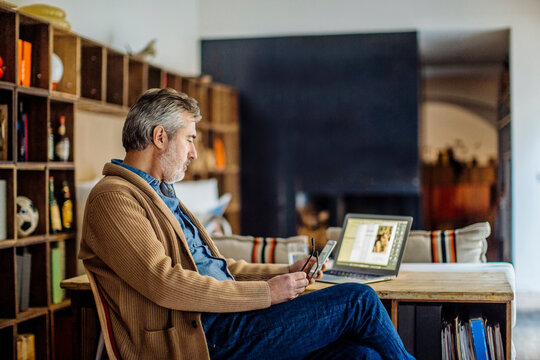 Senior man using smartphone in home office