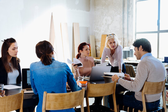 Female boss communicating with employees during meeting