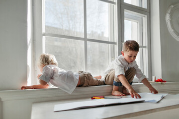 Little boys drawing in the white room.