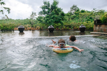 Young boys brothers in a tropical pool.