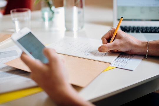 Crop freelancer using smartphone and making notes