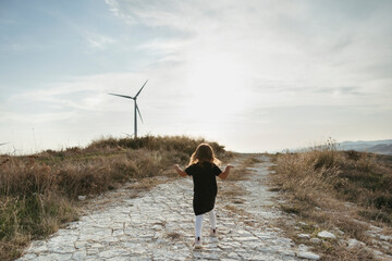 A little girl walking on the road.