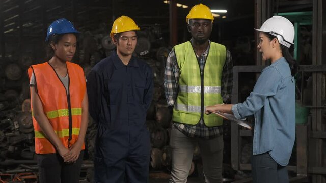 Industrial asian woman engineer talking with group of workers about working safety in factory.