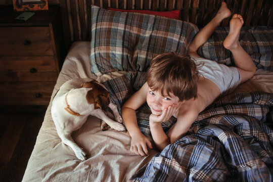 Little boy and his dog on the bed.