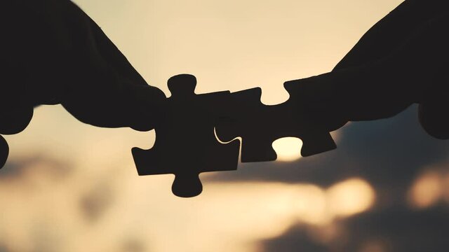 teamwork business finance concept. lifestyle male hands connect two puzzles silhouette against the sunset. teamwork symbol of association and connection. business strategy partnership