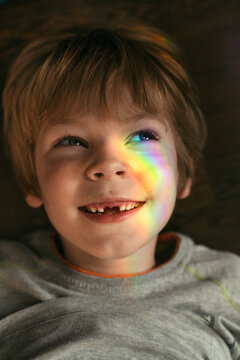 Little boy with rainbow glare on his face.