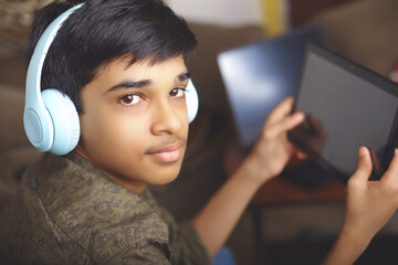 Indian young boy using digital tablet while attending the online classes at home	