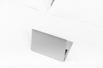 Grey laptop on the bed with white sheets. White background, copy space.