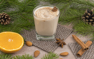 Traditional holiday drink eggnog. sweet drink based on raw chicken eggs and milk. Christmas cocktail with grated nutmeg and cinnamon. background of a spruce branch with cones. xmas drink.