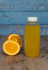 plastic bottle with fresh juice and sliced orange. yellow drink on a wooden background. wooden...
