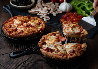 Close up of two individual deep dish pan pizzas with a slice taken out of one.