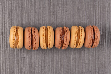 Six coffee and chocolated flavoured macaroons on vinyl background