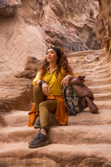 Young beautiful girl tourist sits on the steps of the ancient city in the canyon