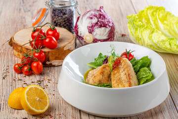 plate with grilled salmon fillets and salad leaves with vegetables on wooden background, close view 