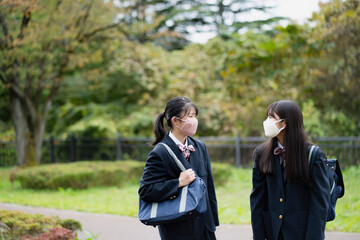 立ち話をするマスクをつけた女子学生2人
