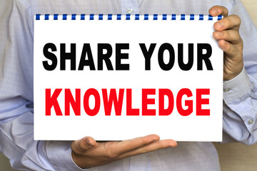 The businessman shows a sheet with the text OF share your KNOWLEDGE on a white background. Business...