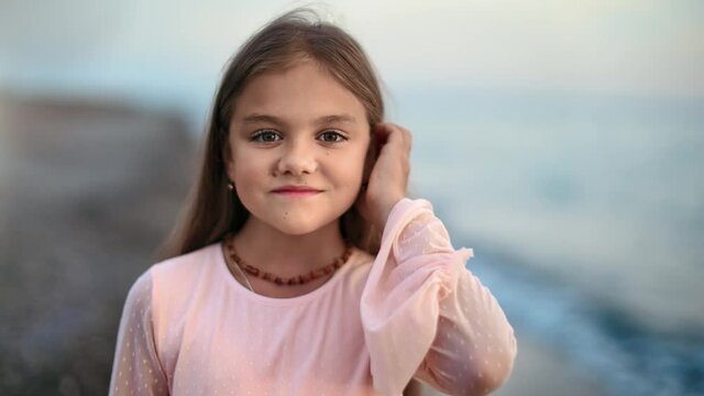 Portrait of little girl smiling posing at sunset sea shore. Medium close up shot on 4k RED camera