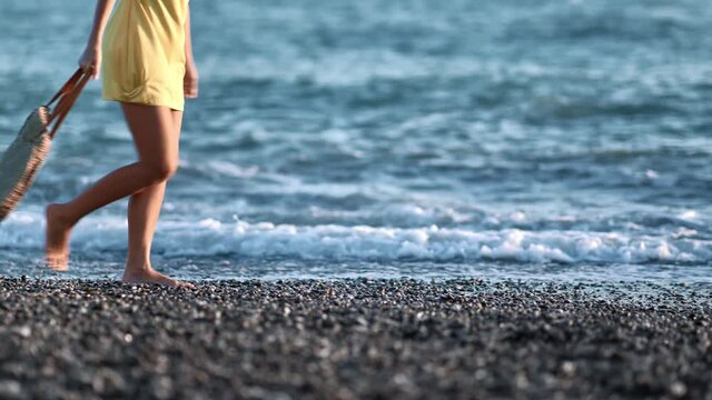 Closeup tanned female legs walking on sea beach at sunset. Shot on RED Raven 4k Cinema Camera