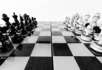 Wooden chess pieces stand on the board in the starting position before the battle.