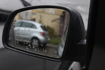 Reflection in the car mirror with raindrops in wet weather