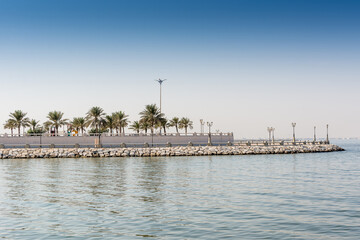 Blue sea and green date palm trees in the corniche park in Dammam, Saudi Arabia