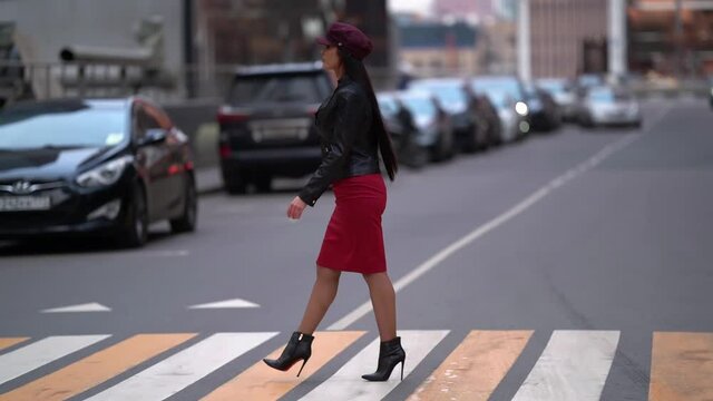 stylish sexy woman is walking on pedestrian crossing in big city, confident gait