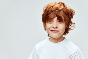 Sly red-haired boy with narrowed eyes conceived something bad white t-shirt cropped view  © SHOTPRIME STUDIO
