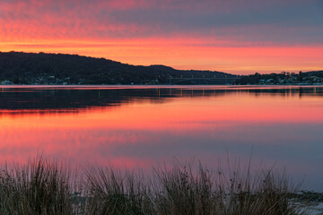 Reflection of Sunrise with soft high cloud over the waterfront